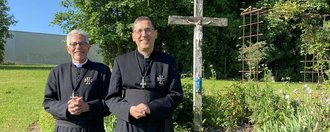 Im Garten: zwei Pfarrer des Ordens lächeln in die Kamera